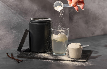 Uma bebida proteica de Beef Protein sendo preparada com um scoop e um copo de água