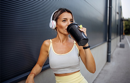 Mulher bebendo immuno whey essential nutrition de uma garrafa de bebida esportiva.