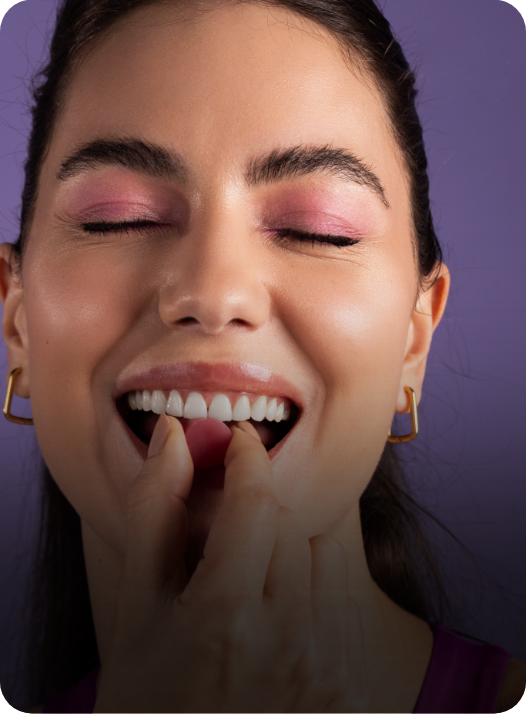 Mulher sorrindo de olhos fechados saboreando uma goma de creatina sabor jabuticaba da essential nutrition
