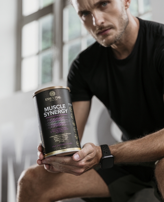 Homem segurando uma lata de Muscle Synergy, suplemento para aumento de força muscular, demonstrando foco e determinação.