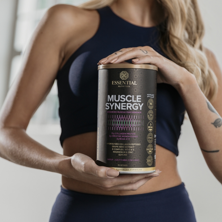 Mulher loira vestindo top esportivo preto e leggings, segurando uma lata de Muscle Synergy.