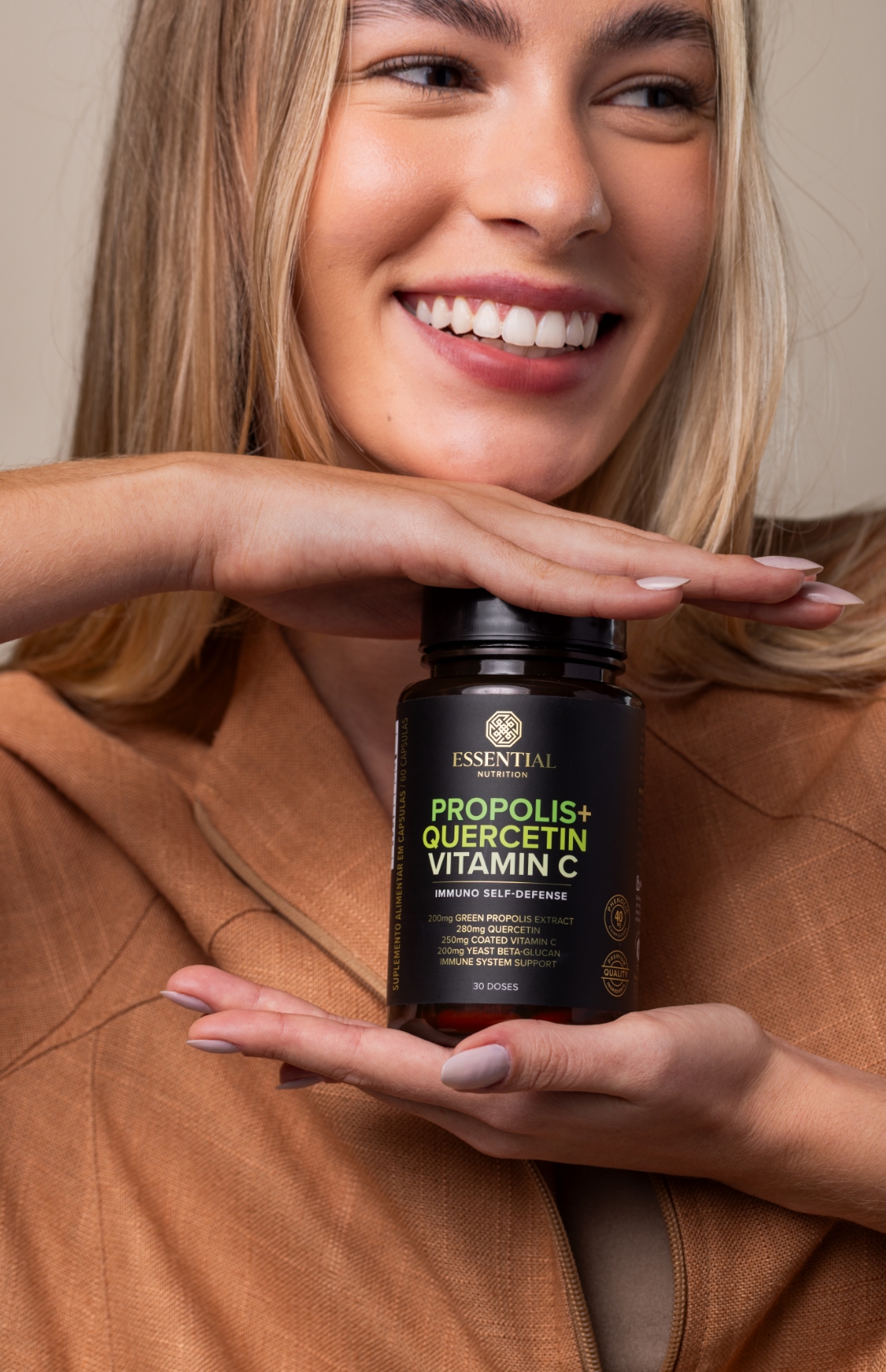 mulher sorrindo segurando um pote de própolis verde da essential nutrition